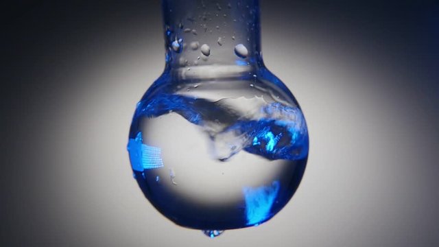 An astonishing macro shot of clean water in a round bottom flask shaken in a medical lab. The water plays with blue and grey tints