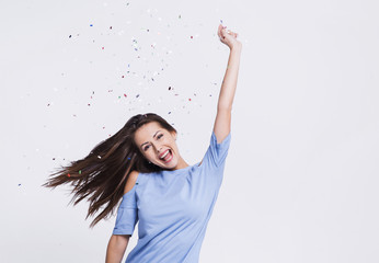 Beautiful happy woman at celebration party with confetti falling everywhere on her. Birthday or New...