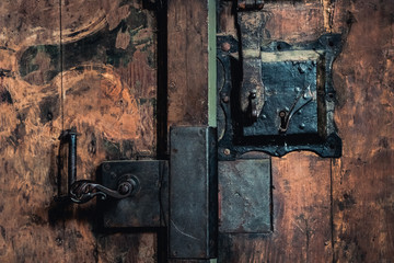 Close-up photo of an old rusty metal lock mechanism on a wooden door.