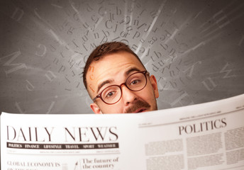 Young smart businessman reading daily newspaper with alphabet letters above his head