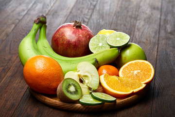 Ripe fresh fruits in a wooden plate on a rustic wooden background, selective focus, close-up, top view