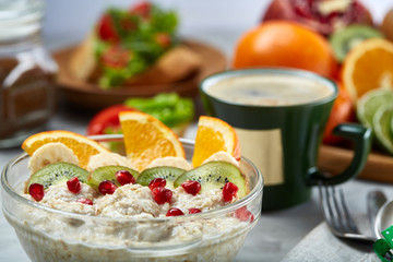 Breakfast still life with oatmeal porridge, fruits and coffee cup, top view, selective focus, shallow depth of field.