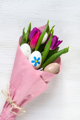 Tulips and Easter eggs on a white wooden background. Easter background.