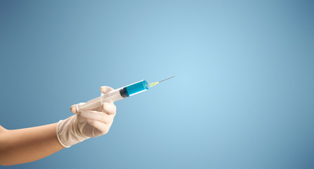 Female doctor hand holding syringe with blue background