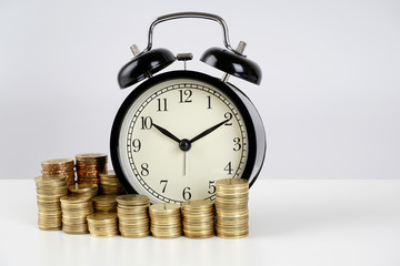 Alarm clock and coins on a white surface