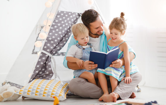 family father reading to children book in tent at home