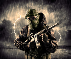 Portrait of a dangerous armed terrorist with mask and gun in a thunderstorm with lightning