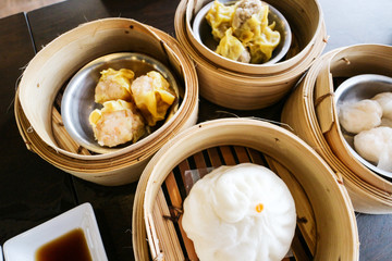 Dim sum put in the bamboo streaming with it sauce all put on the wood table in chinese resturant