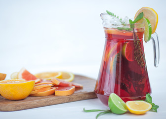 tasty and juicy sangria with citrus in a glass next to the pitcher on a white background...