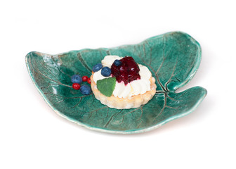 Tart with berry cream and blueberries on a ceramic plate on a white background