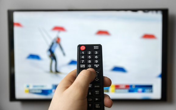 Male hand holding TV remote control. Biathlon.