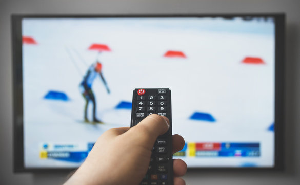 Male hand holding TV remote control. Biathlon.