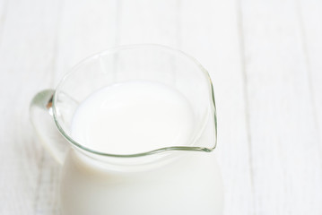 Fototapeta na wymiar Milk jug on white wooden table