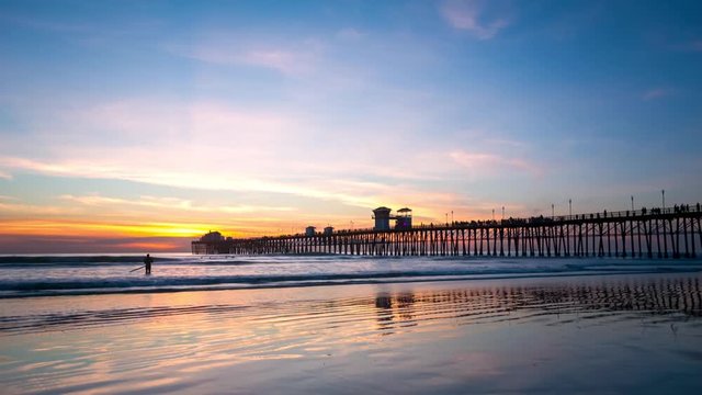 California Oceanside pier at sunset with reflections on wet beach sand