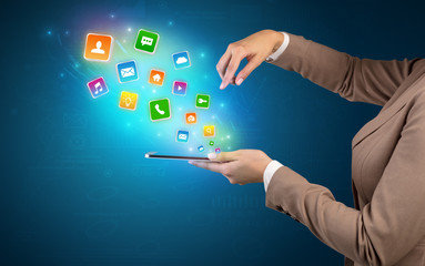 Hand holding tablet and application icons falling inwards