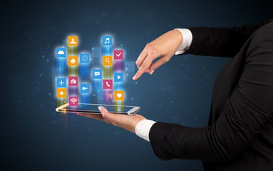 Female elegant hand holding tablet with colourful application icons