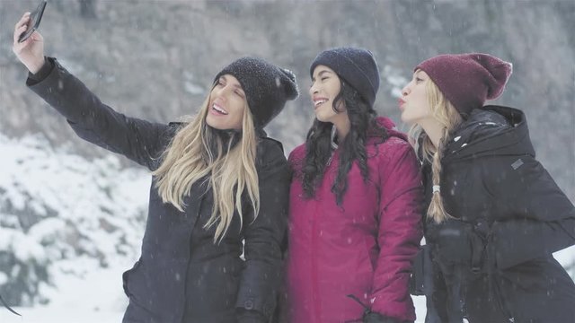 Three young beautiful ladies taking a selfie together on a snowy day
