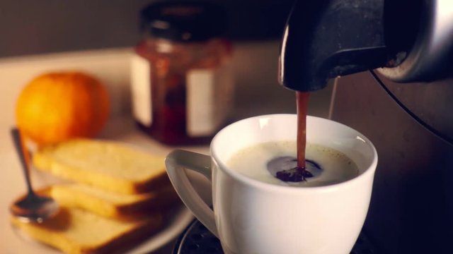 Slowmotion breakfast scene.Coffee maker pouring fresh espresso coffee in a cup at breakfast. 240 fps footage.