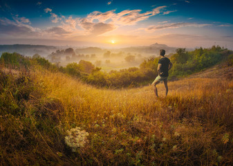 Man standing on a hill in a high graass