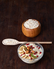 Diet breakfast oatmeal with fruits, bowl and spoon with oat flakes, selective focus, close-up