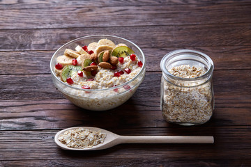 Diet breakfast oatmeal with fruits, bowl and spoon with oat flakes, selective focus, close-up