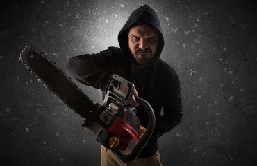 Masked armed villain in empty dark room with gun ax chainsaw mallet wrench
