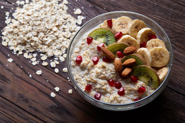 Diet breakfast oatmeal with fruits, bowl and spoon with oat flakes, selective focus, close-up
