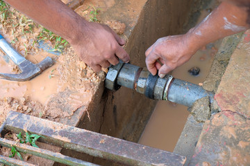 Workers repairing leaked galvanized steel pipes using pipe work hand tools