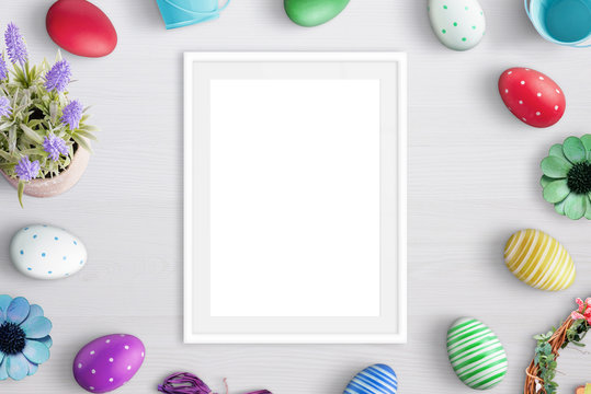 Blank picture frame surrounded with easter eggs and flowers.