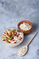 Diet breakfast oatmeal with fruits, bowl and spoon with oat flakes, selective focus, close-up