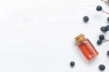 Wild black berry essential oil on white wooden surface background. Herbal medicine. Alternative medicine.
