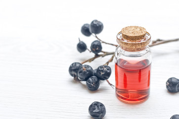 Wild black berry essential oil on white wooden surface background. Herbal medicine. Alternative medicine.