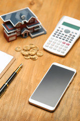 house model,calculator,pen,and coins on wooden table