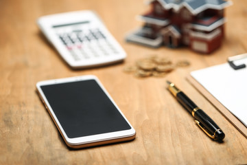 house model,calculator,pen,and coins on wooden table