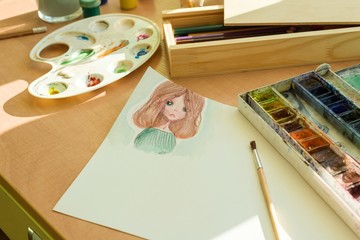 Fototapeta na wymiar Drawing by watercolor - anime girl, on a table with watercolor paint brush