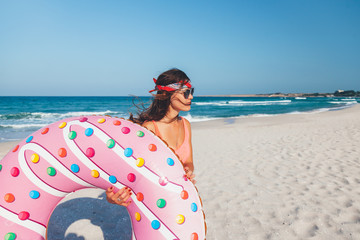Girl with donut lilo on the beach