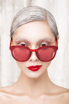 Fashion portrait of a beautiful girl with red lips and red glasses