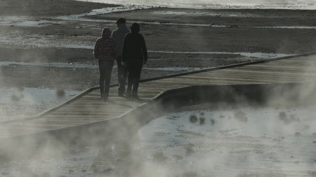 Three people walking on a boardwalk