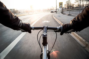 First-person view of cyclist in the city at morning - obrazy, fototapety, plakaty