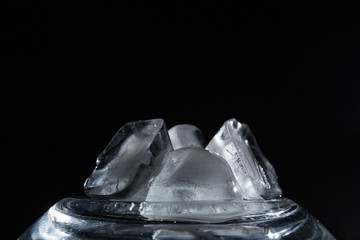 Ice cubes on a black background and a transparent stand close-up.
