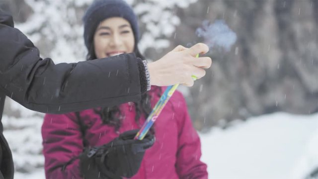 Beautiful young ladies light up a roman candle on a snowy day