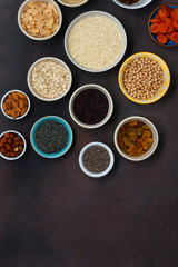 Obraz na płótnie Canvas Top view set vegetarian healthy food - different superfood, seeds and cereal on dark background with copy space. Flat lay. Clean eating concept
