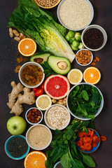 Top view set clean eating. Vegetarian healthy food - different vegetables and fruits, superfood, seeds, cereal, leaf vegetable on dark background. Flat lay