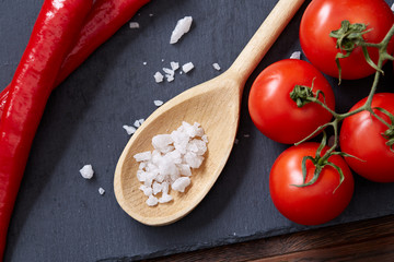 Vegetarian still life with fresh grape tomatoes, pepper and salt in wooden spoon on wooden background, selective focus