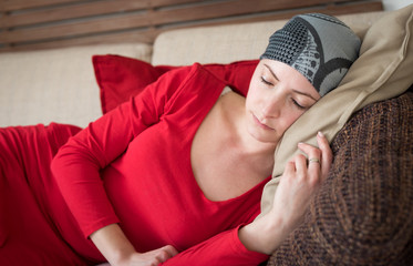 Young adult female cancer patient relaxing on a couch. Tired, exhausted, depressed cancer patient.