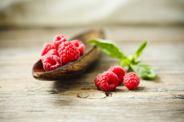 Fresh sweet raspberry and green basil in a wooden plate. Horizontal.
