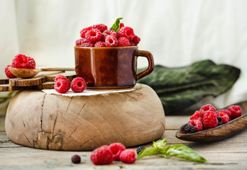 Organic raspberry with basil in a cup of coffee and a wooden stand.Detox diet food and raw vegan concept.Horizontal.