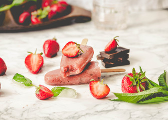Strawberry ice cream with a banana and chocolate on a stick. Summer fresh dessert. Mint. Tone.Selective focus.