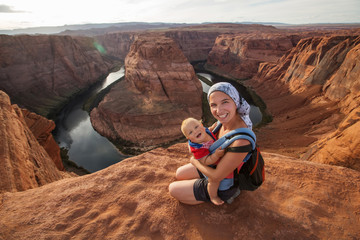A mother and her baby boy are sitting at the edge of the cliff near Horseshoe band landmark,...