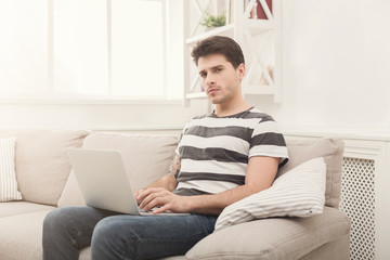 Fototapeta premium Young man at home messaging online on laptop